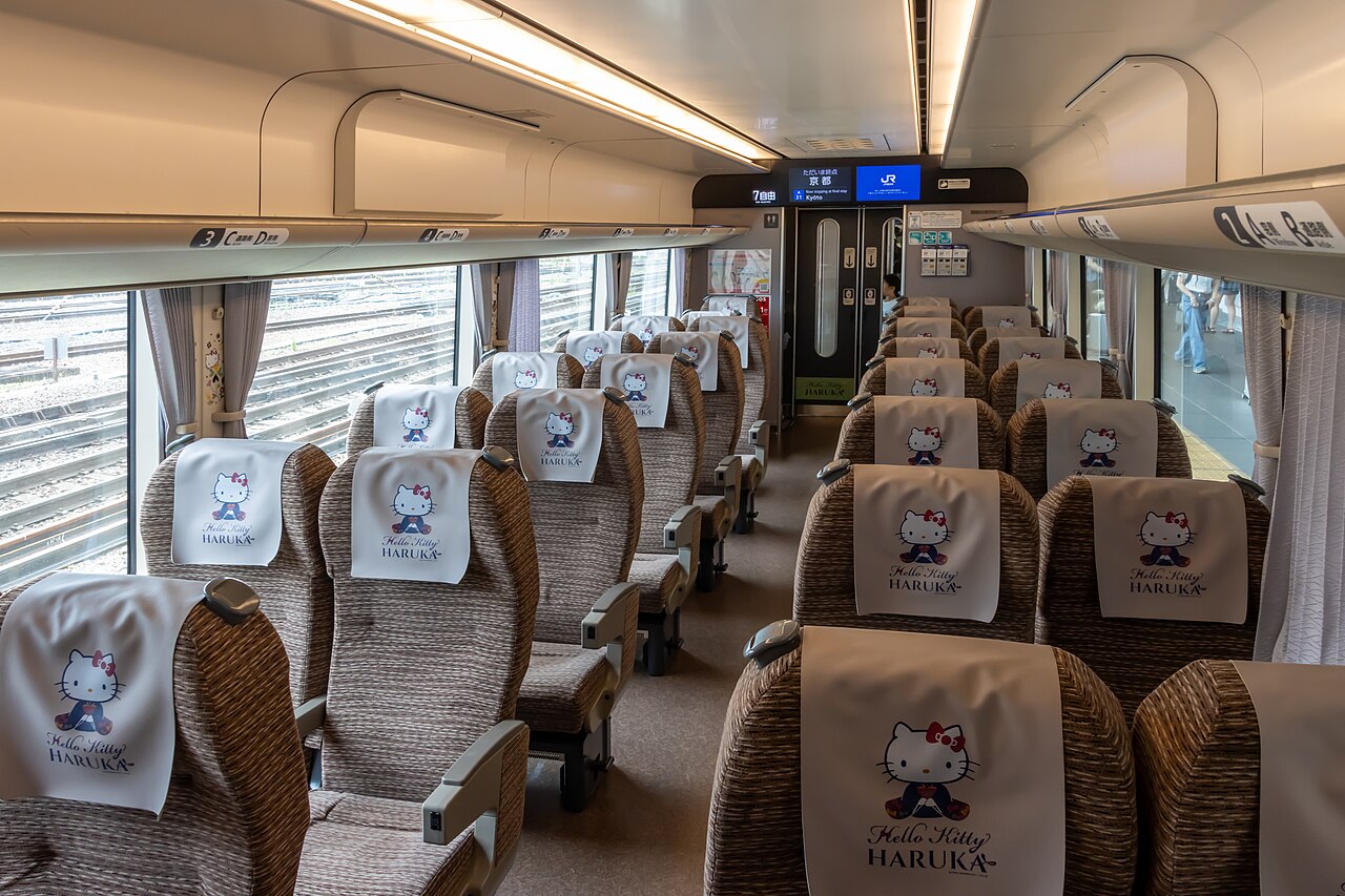 Interior view of an empty Hello Kitty themed train carriage with rows of passenger seats.