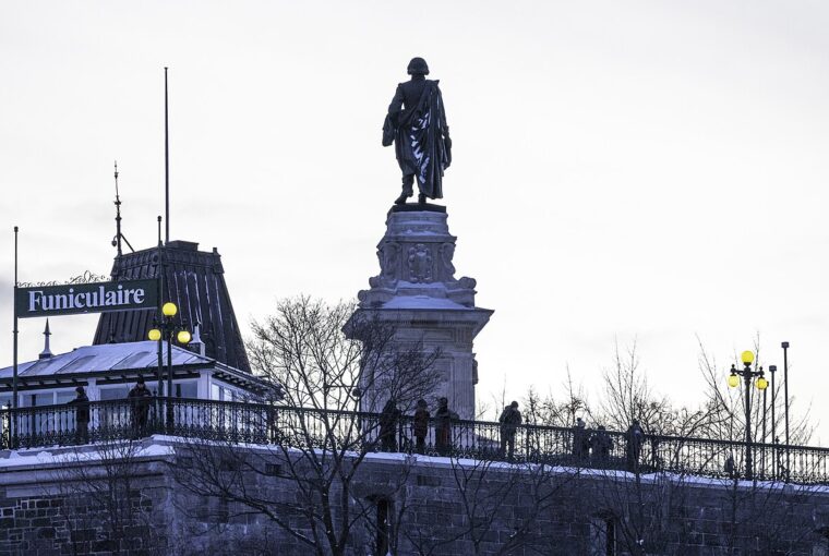 A statue of Samuel de Champlain stands near a sign for the funicular in Old Quebec.