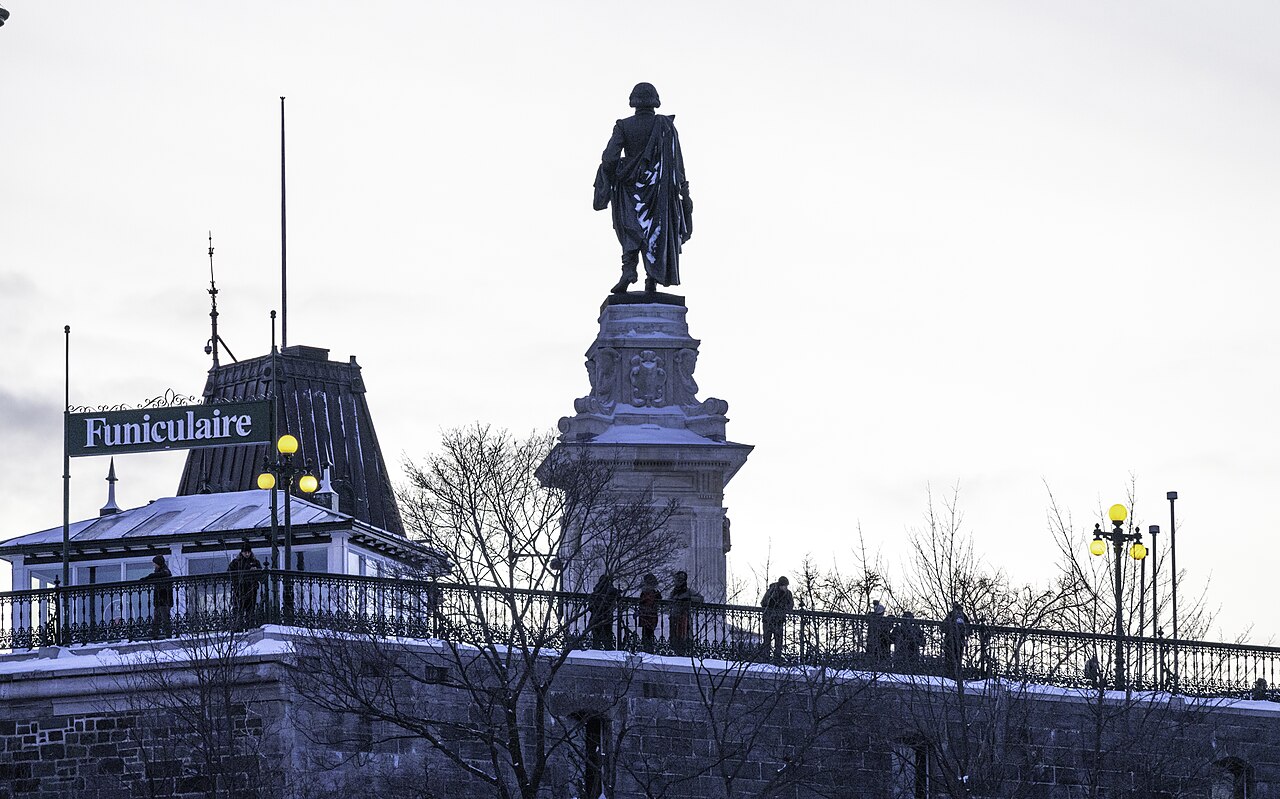 A statue of Samuel de Champlain stands near a sign for the funicular in Old Quebec.