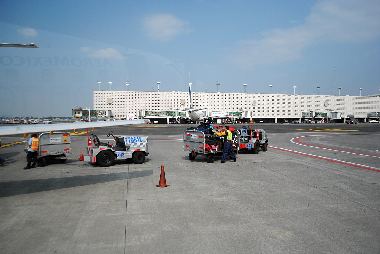 Airport ground crew loading baggage carts near an airplane on the tarmac at an airport terminal.